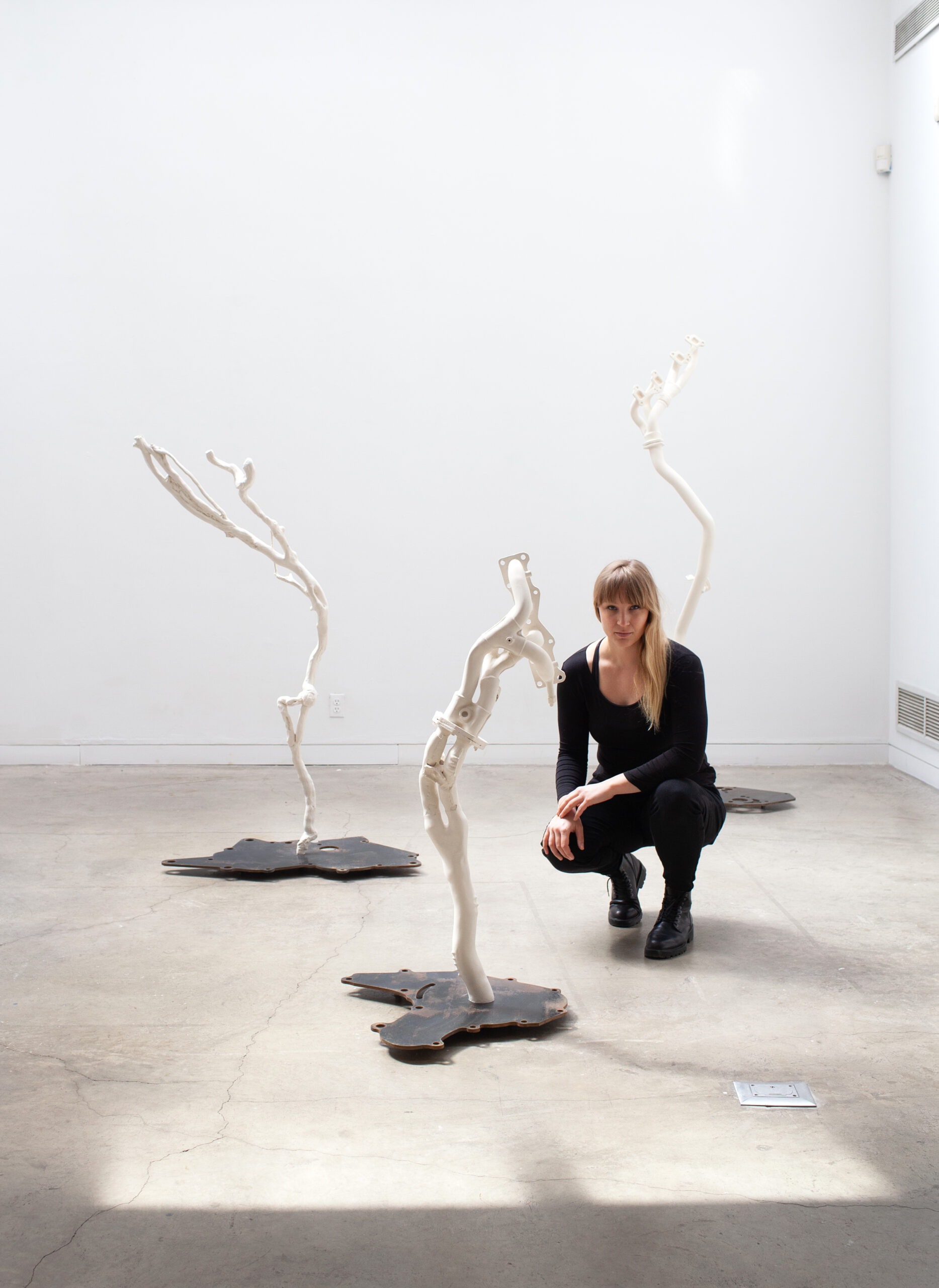 Katja Larsson sitter på huk bredvid skulpturer.