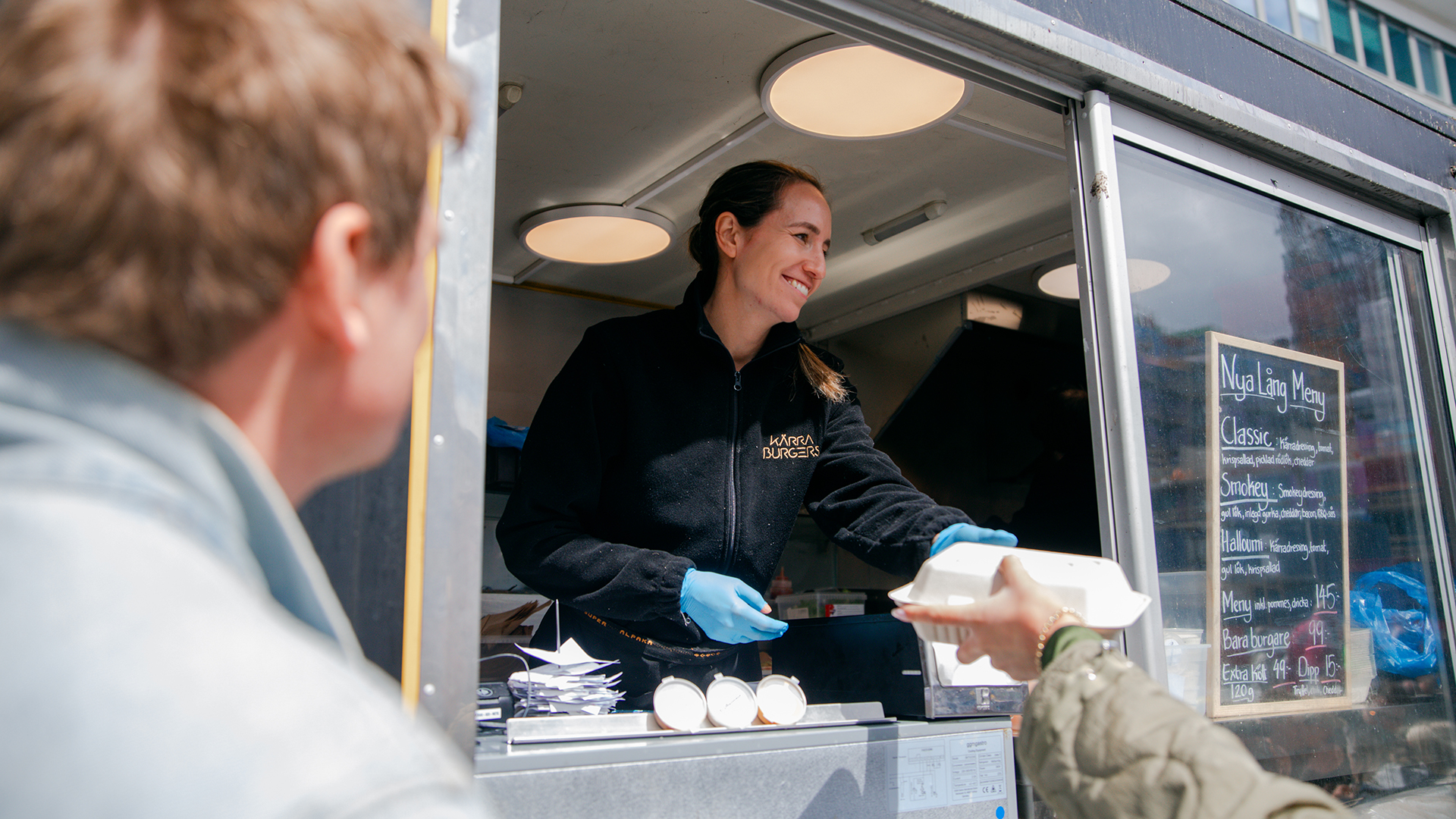 Person i food truck delar ut en låda med mat